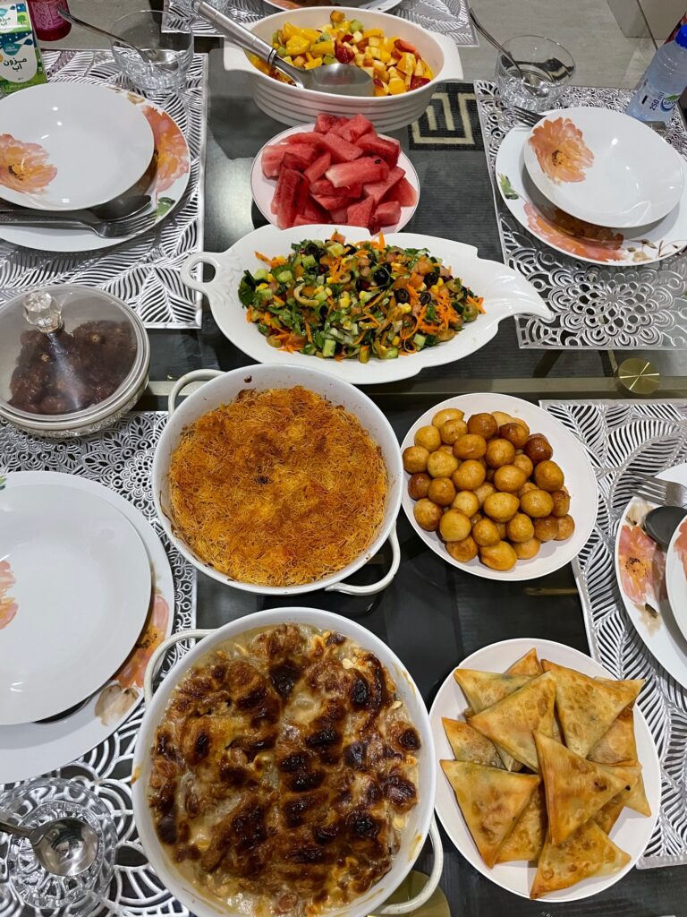An Iftar meal includes samosas, luqaimat, and Um Ali
