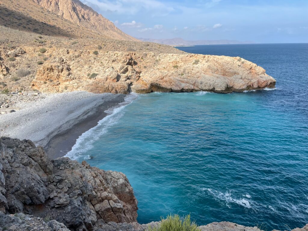 Panoramic sea view onto a small empty beach and rocky coastline while hiking.