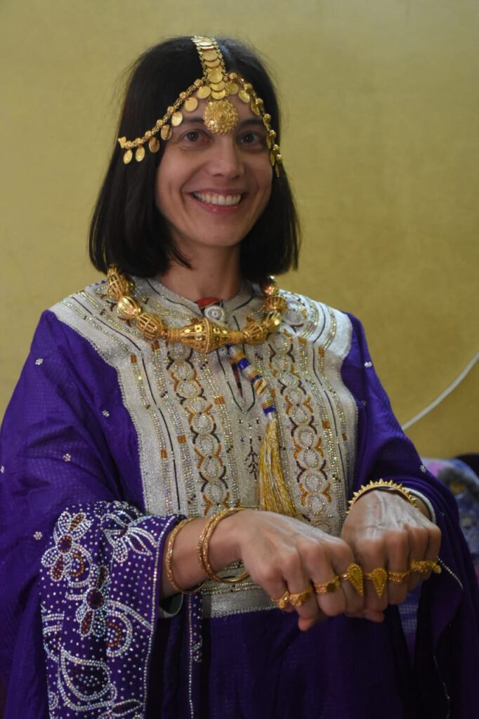 dressed in a purple traditional dress wearing gold rings and a head piece