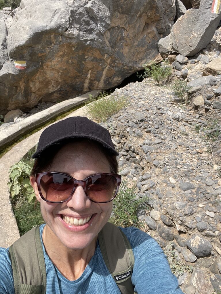 Erin standing in front of the filaj and a few rocks. 6 wadis to cool off in Oman