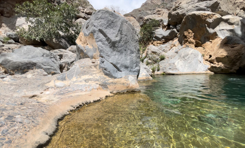 boulders and trees surround a small pool of turquoise colored water