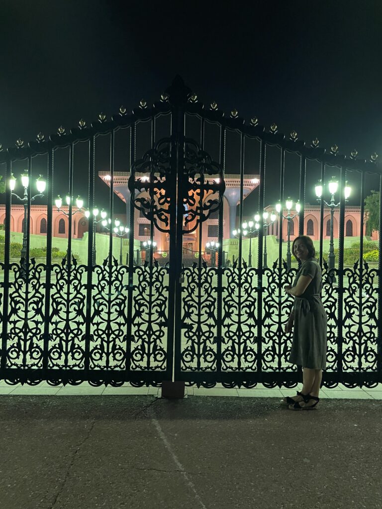 Erin standing outside the gate of the Alam Palace. The lights make the ground appear green