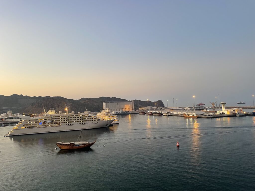 A yacht and dhow are docked in the harbor