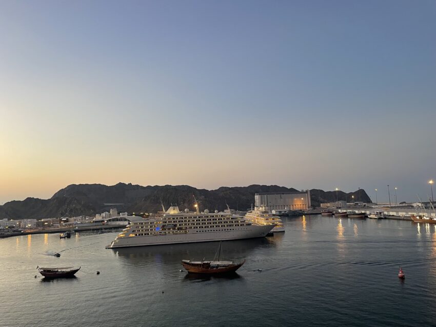 Fishing boats, a dhow, and a yacht are docked in the harbor