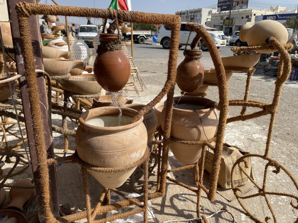 A string bicycle holds clay water pitchers that could be used for an outside garden