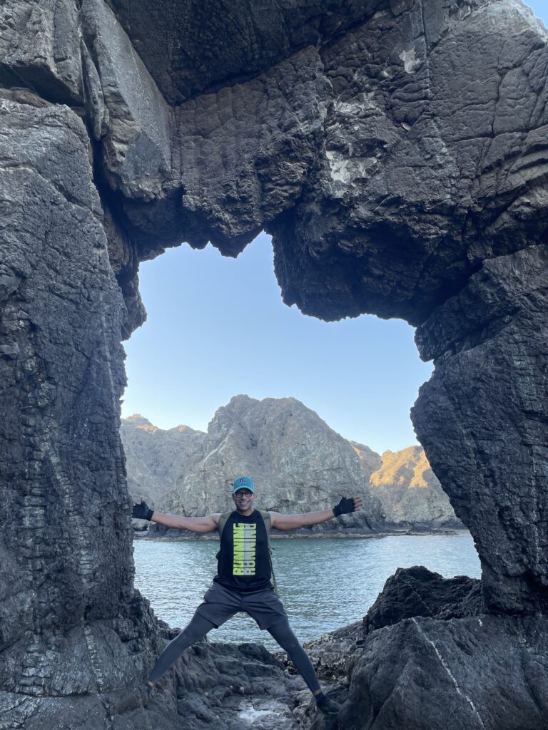 Walks and hikes in Muscat. Freddy is standing in between an arched rock